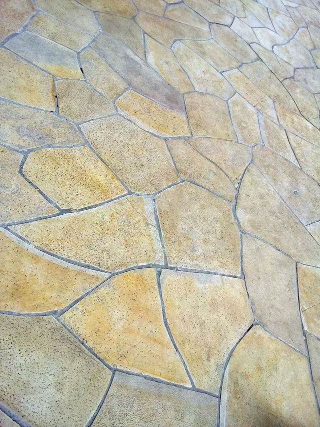 Tan and beige stone pavers laid in a mosaic pattern.