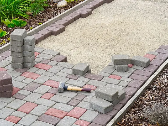 Path construction: bricks in progress, alternating red/gray, hammer visible, outdoor setting.